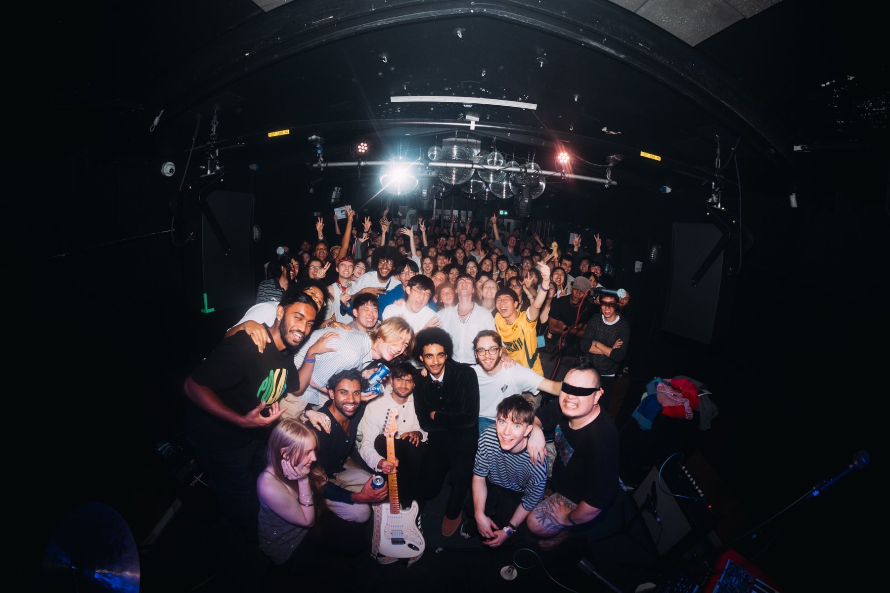 Both bands and the whole crowd piled together on stage for a group photo under the mirrorball
