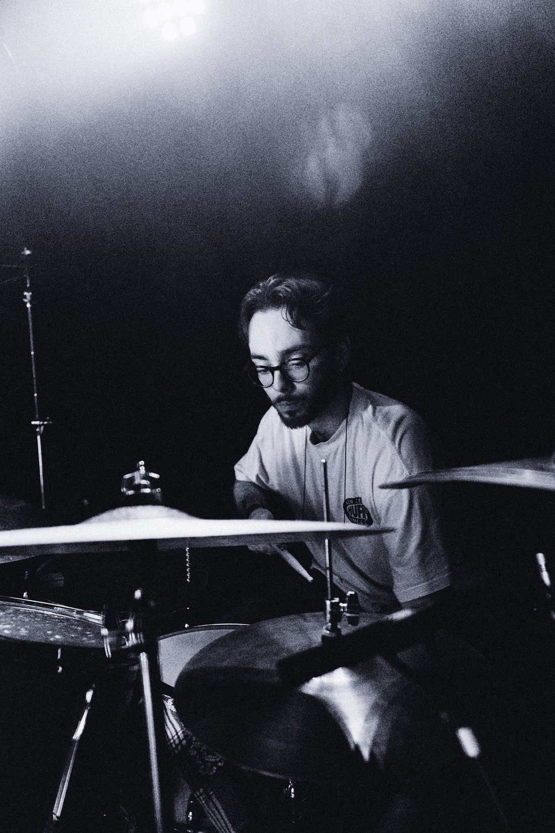 Drummer mid-phrase behind the kit in black and white